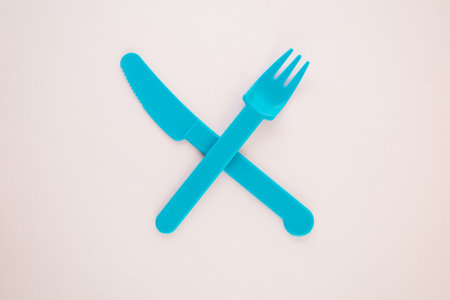 High angle view of fork and knife crosses on pink background. Minimal food concept.の写真素材