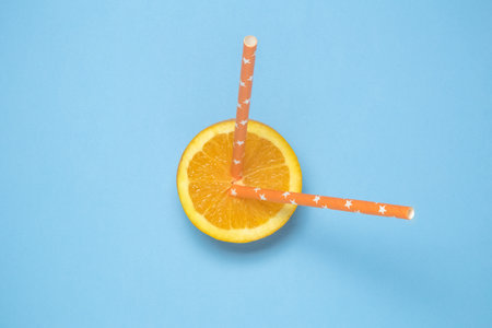 Flat lay of orange fruit with two drinking straws on pastel blue background minimal conceptの写真素材