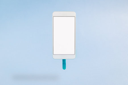 Mobile phone in form of ice cream isolated on pastel blue background minimal concept.の写真素材