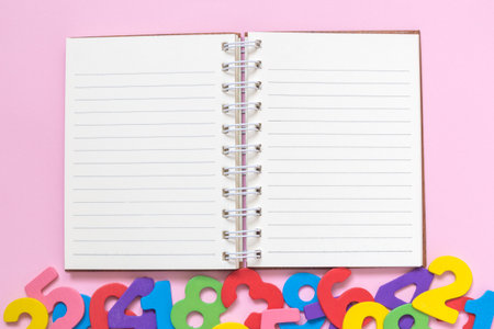 Open notepad and colorful numbers against pastel pink background flat lay minimal creative concept. Space for copy.の写真素材