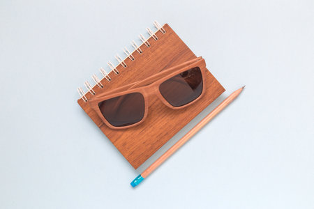 Wooden notepad, sunglasses and pencil on colorful background minimal creative flat lay concept.の写真素材