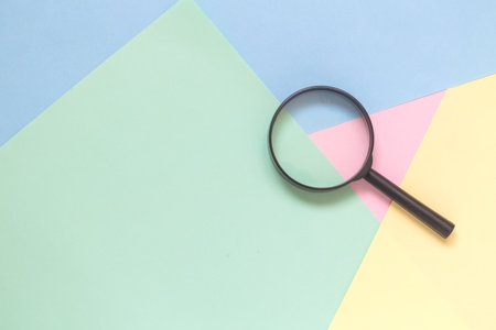 Magnifying glass against colorful pastel background flat lay minimal creative concept.の写真素材