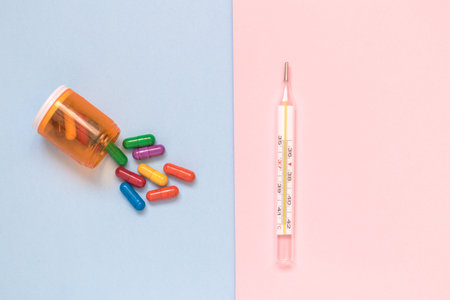 Thermometer and colorful pills on pastel background minimal creative concept.の写真素材