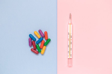 Thermometer and colorful pills on pastel background minimal creative concept.の写真素材