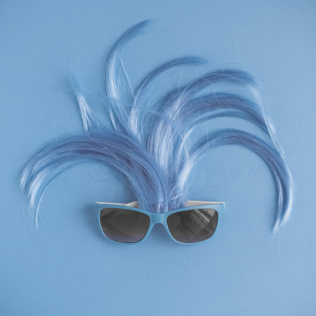 Flat lay of sunglasses and hair minimal blue creative summer concept.