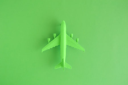 Flat lay of miniature toy airplane on neon green background minimal trip and travel creative...