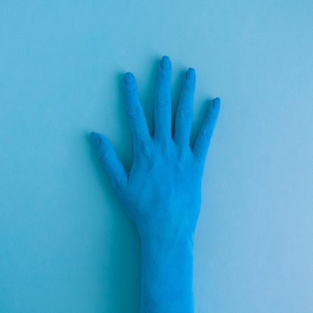 Close up of female hand colored in blue paint minimal creative concept.の写真素材