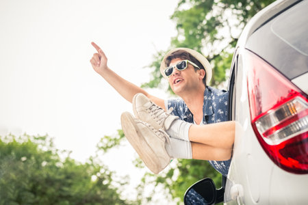 Hipster man and legs out of car windows. On the road summer vacation trip concept.の写真素材