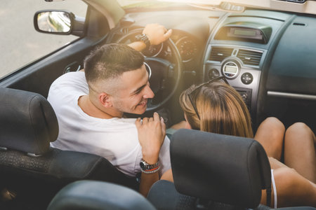 High angle view of beautiful young couple sitting in cabriolet car.