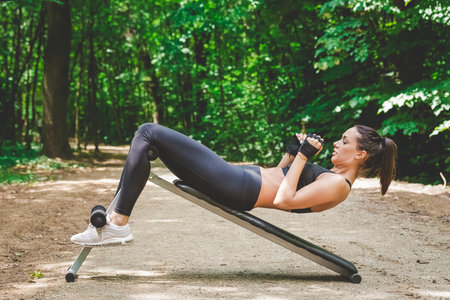 Sportswoman doing sit ups in nature. Exercise healthy lifestyle concept.