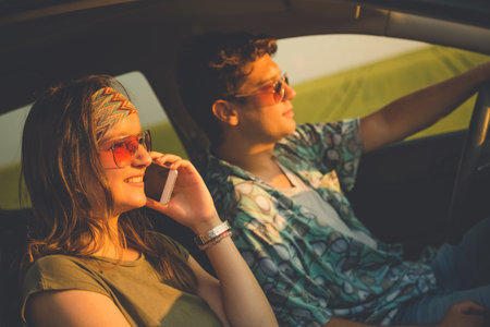 Beautiful couple in car driving and using smartphone. Travel and technology concepts.の写真素材