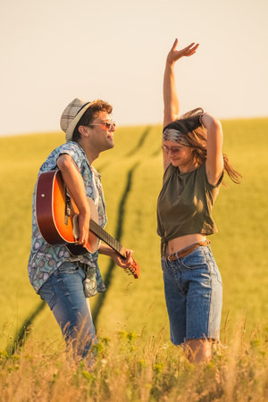 Romantic hipster couple singing their favorite song in nature. Love and summertime concept.の写真素材