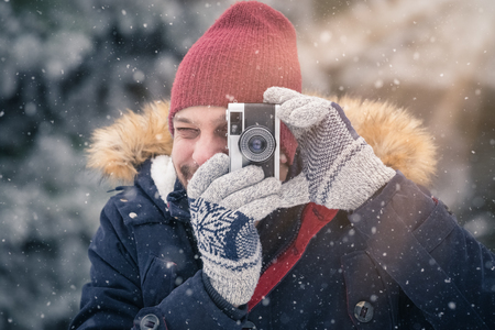 Young man with vintage photo camera in nature. Winter scene background.