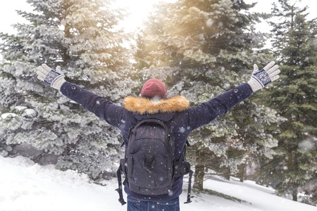 Rear view of tourist with arms up against winter background.の写真素材