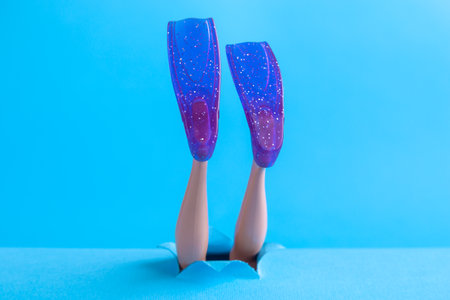 Doll legs with snorkel fins on blue sea background minimal creative abstract concept.の写真素材