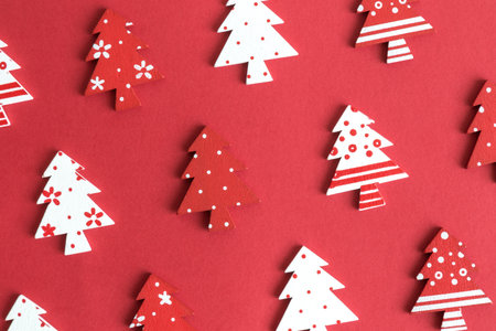 Flat lay of wooden christmas trees pattern on red background minimal creative concept.の写真素材