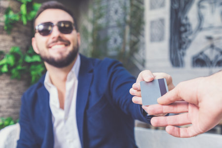 Successful handsome businessman paying bill with credit card in cafe.の写真素材