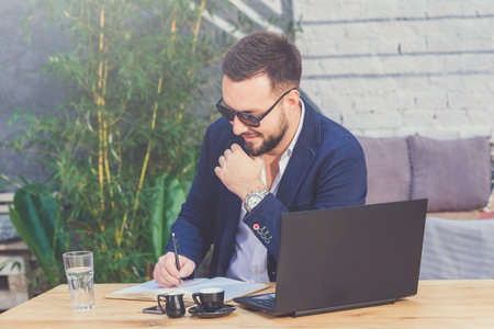 Businessman writing notes in notepad at coffee shop.の写真素材
