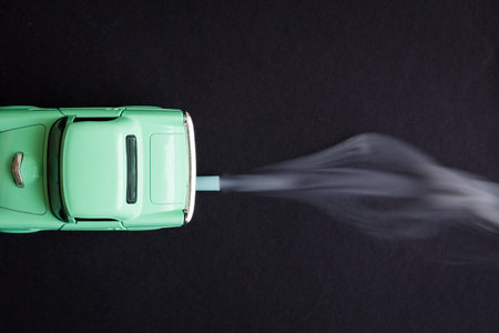 Flat lay of car toy emitting smoke CO2 from exhaust pipe on dark background minimal creative concept.の写真素材