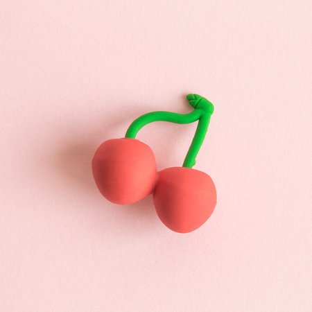 Flat lay of cherry fruit toy on pastel pink background minimal creative concept.の写真素材