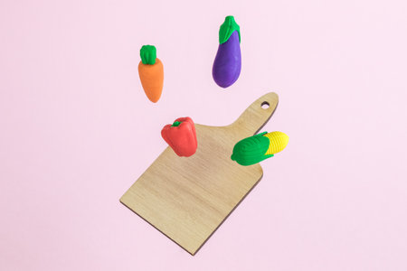 Flying vegetables with wooden cutting board abstract on pastel pink background minimal food preparation cooking creative concept.の写真素材