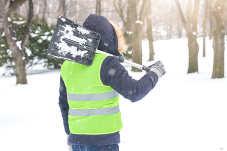 Rear view of man holding shovel over his shoulder and preparing for shoveling snow.