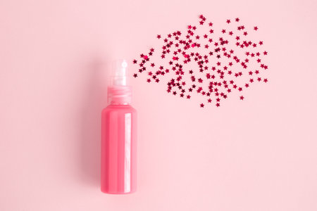 Bottle of perfume with spray of small stars on pastel pink background minimal creative concept.の写真素材