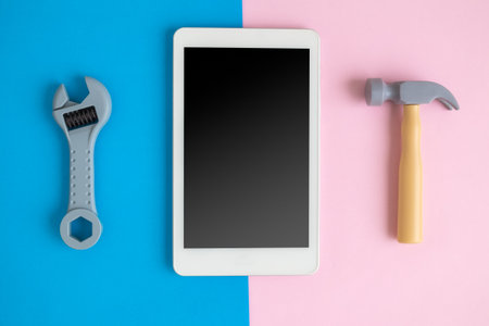 Digital tablet device or mobile phone with hammer and wrench on pastel background minimal technology...