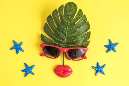 Face abstract made of summer vacation accessories on yellow background minimal creative travel concept.の写真素材