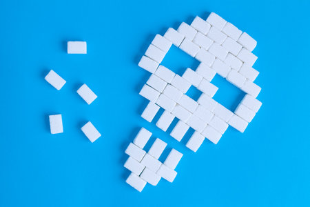 Flat lay of skull made of sugar cubes on blue background unhealthy food minimal creative concept.の写真素材