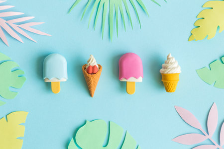 Summer background made of ice cream miniatures and colorful paper tropical leaves minimal creative concept.の写真素材