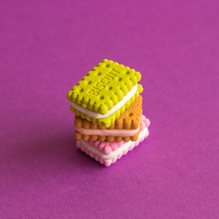 Miniature biscuits stack against purple background minimal creative sweet food concept.