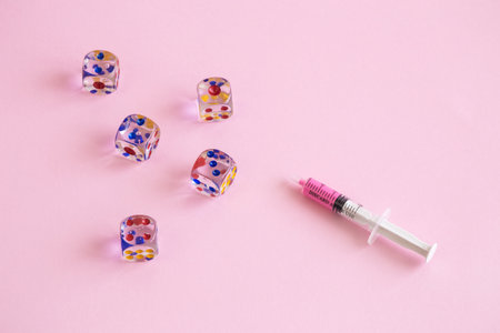 Gaming dices and syringe against pastel pink background minimal drug abuse and gambling creative...