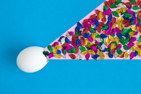 Egg shell with colorful leaves on blue background minimal easter and spring creative concept.の写真素材