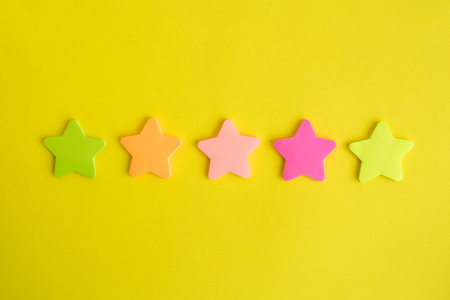 Five colorful stars on yellow background minimal rating creative concept. Space for copy.
