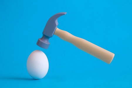 White egg and plastic hammer toy on pastel blue background minimal creative concept.の写真素材