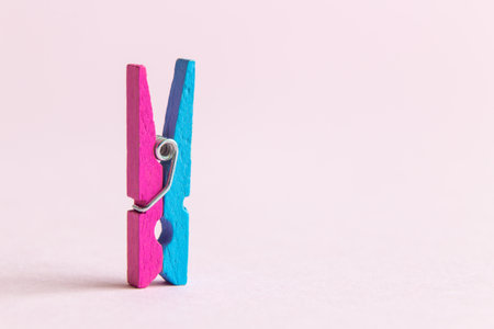 Close up of colorful clothespin against pastel pink background minimal creative concept. Space for...