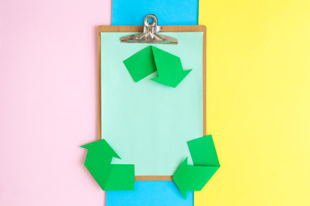 Flat lay of blank clipboard and recycle symbol made of paper on colorful background minimal creative ecology concept.の写真素材