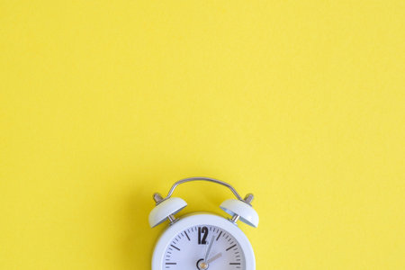 White clock on yellow background. Space for copy. Minimal concept.の写真素材