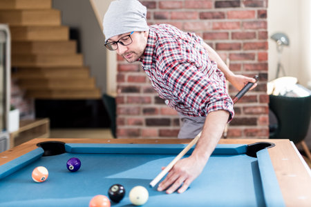 Fashionable hipster guy playing pool billiard game at the office chill room.の写真素材