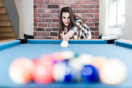 Portrait of young female playing billiards.