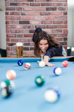 Portrait of pretty young female playing billiards.