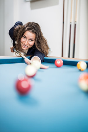 Portrait of beautiful young female playing billiards. Space for copy.の写真素材