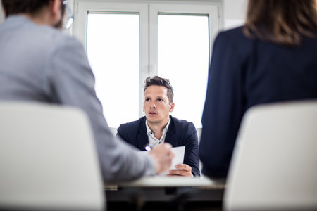 Portrait of young businessman discussing with his colleagues at the desk in meeting or conference room.の写真素材