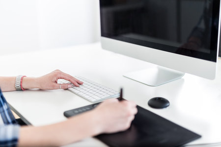 Graphic designer drawing on pad and pressing a button on computer keyboard.の写真素材