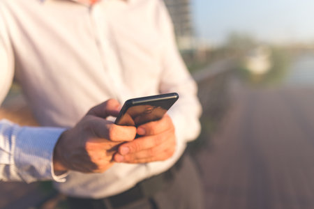 Close up of businessman using smartphone outdoors.の写真素材