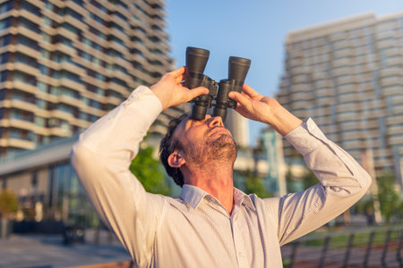 Businessman watching through binoculars outdoors. Business vision concept.の写真素材