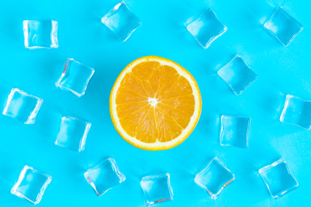 Flat lay of orange fruit slice and ice cubes on blue background minimal creative summer orangeade drink concept.の写真素材