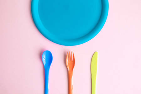 Plastic cutlery with plate against pastel pink background minimal creative food concept.の写真素材