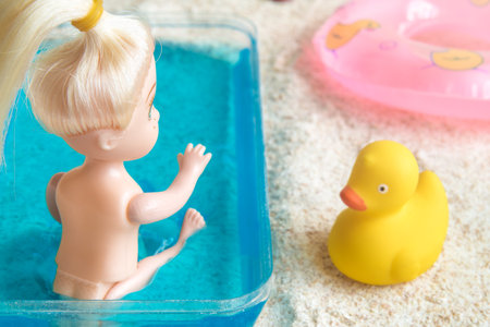 Rear view of baby doll bathing in kids swimming pool at the beach minimal creative summer vacation concept.の写真素材